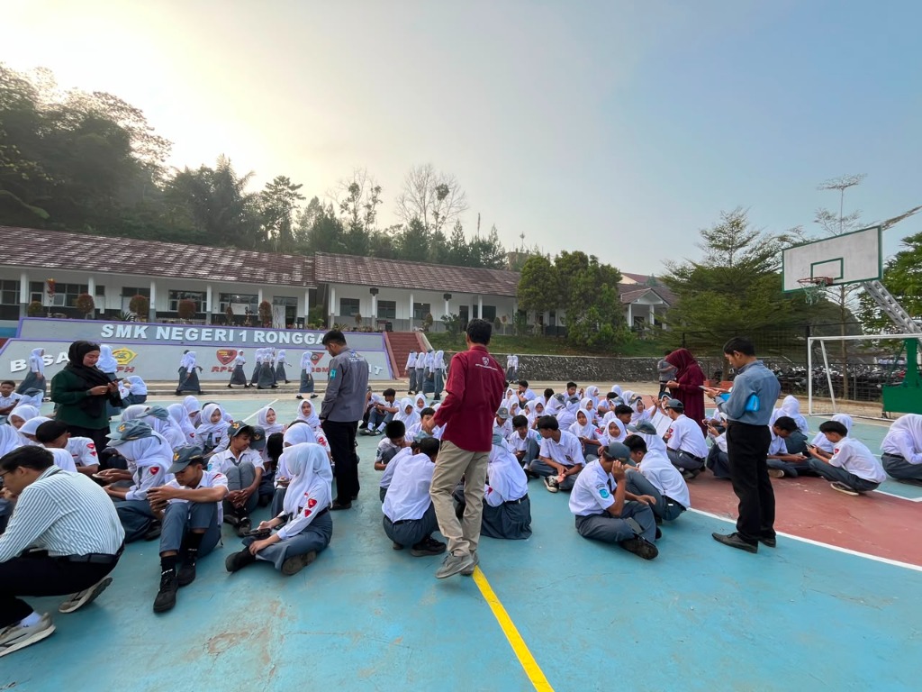 Guru-guru SMKN 1 Rongga memberikan sosialisasi dan bimbingan teknis penggunaan aplikasi Jingga Absensi kepada siswa yang duduk rapi di lapangan