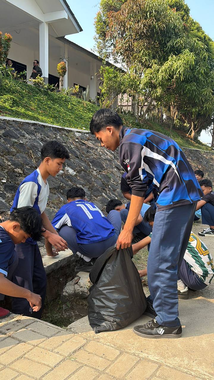 Siswa putra SMKN 1 Rongga bahu-membahu memegang kantong sampah hitam besar menampung sisa rumput dan gulma
