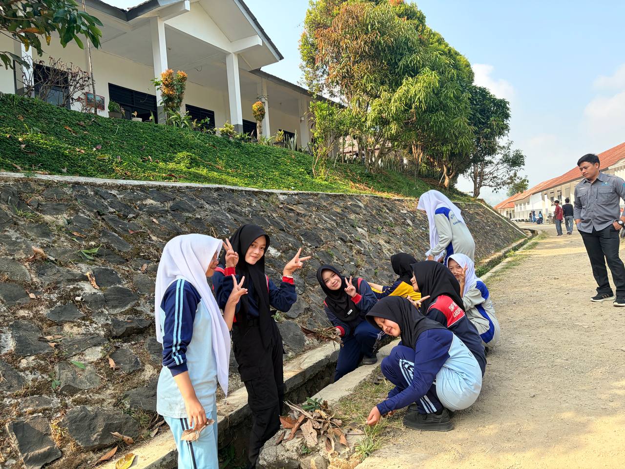Guru pembina SMKN 1 Rongga mendampingi jalannya kerja bakti pembersihan pekarangan sekolah bersama siswa