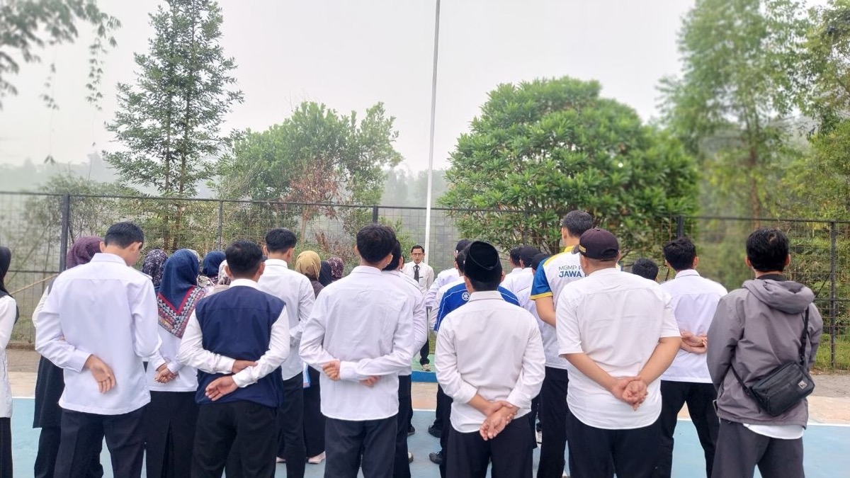 Perspektif barisan GTK menghadap tiang bendera dan pepohonan hijau saat apel pagi berlangsung