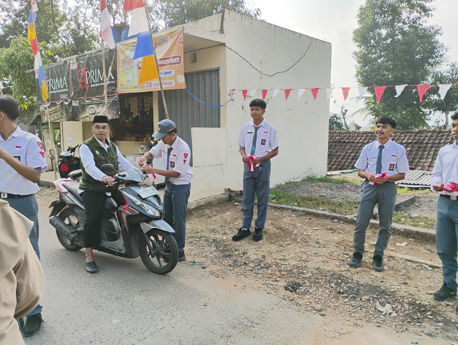 Guru SMKN 1 Rongga mendampingi siswa membagikan bendera merah putih kepada pengendara motor di jalan