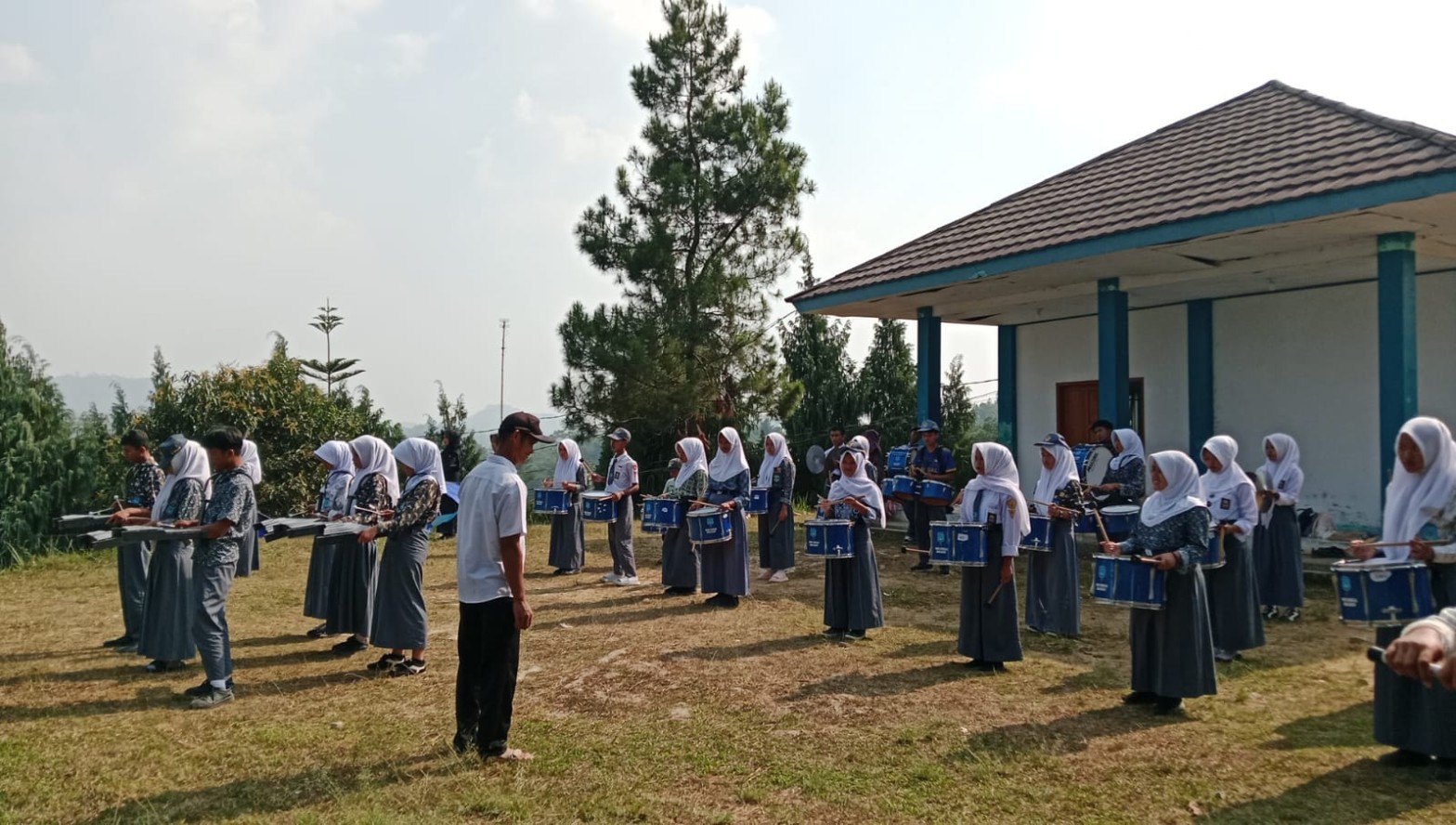 Barisan siswa drumband SMKN 1 Rongga berlatih dengan instrumen perkusi di lapangan sekolah