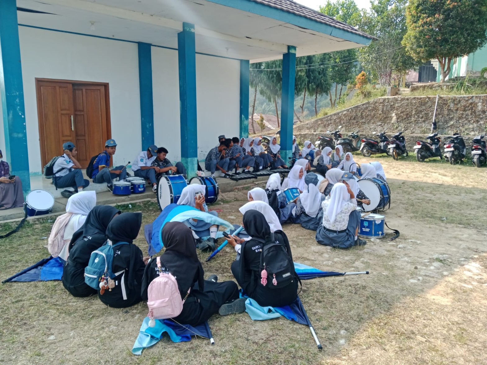 Siswa drumband SMKN 1 Rongga beristirahat bersama di lapangan sekolah setelah latihan