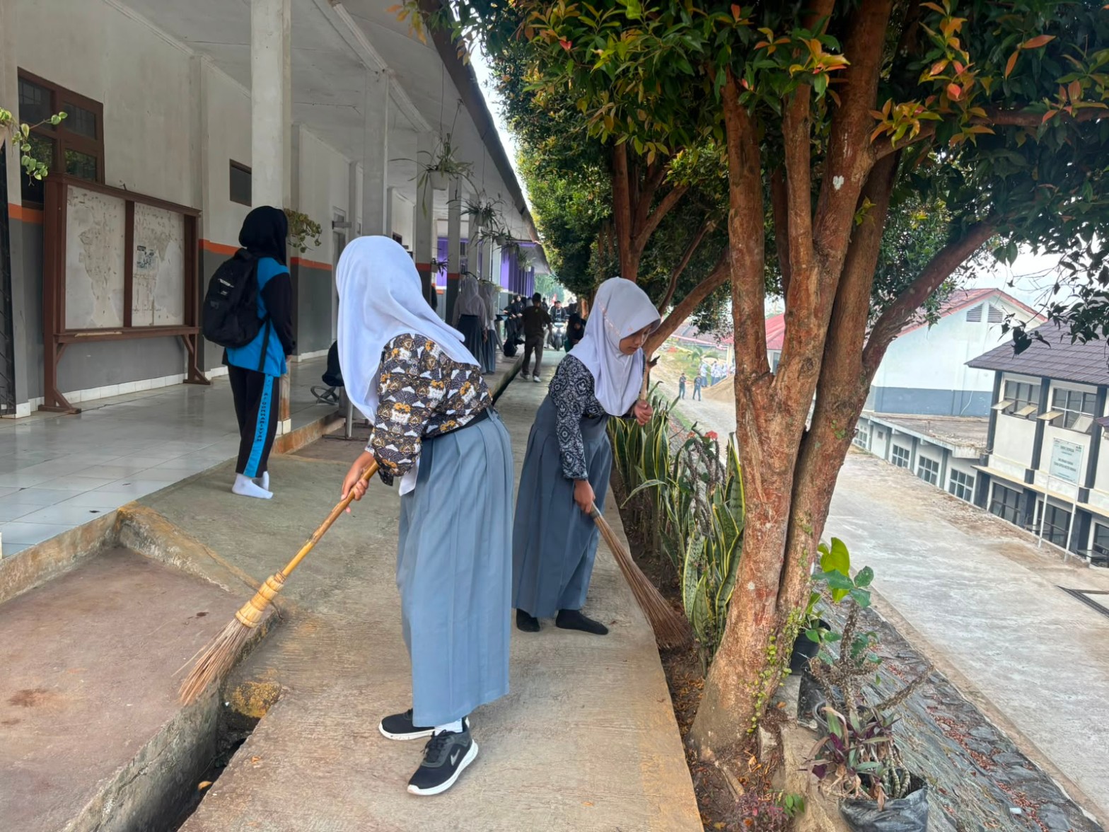 Dua siswi menyapu koridor sekolah dengan sapu lidi pada kegiatan Kamis Bersih SMKN 1 Rongga