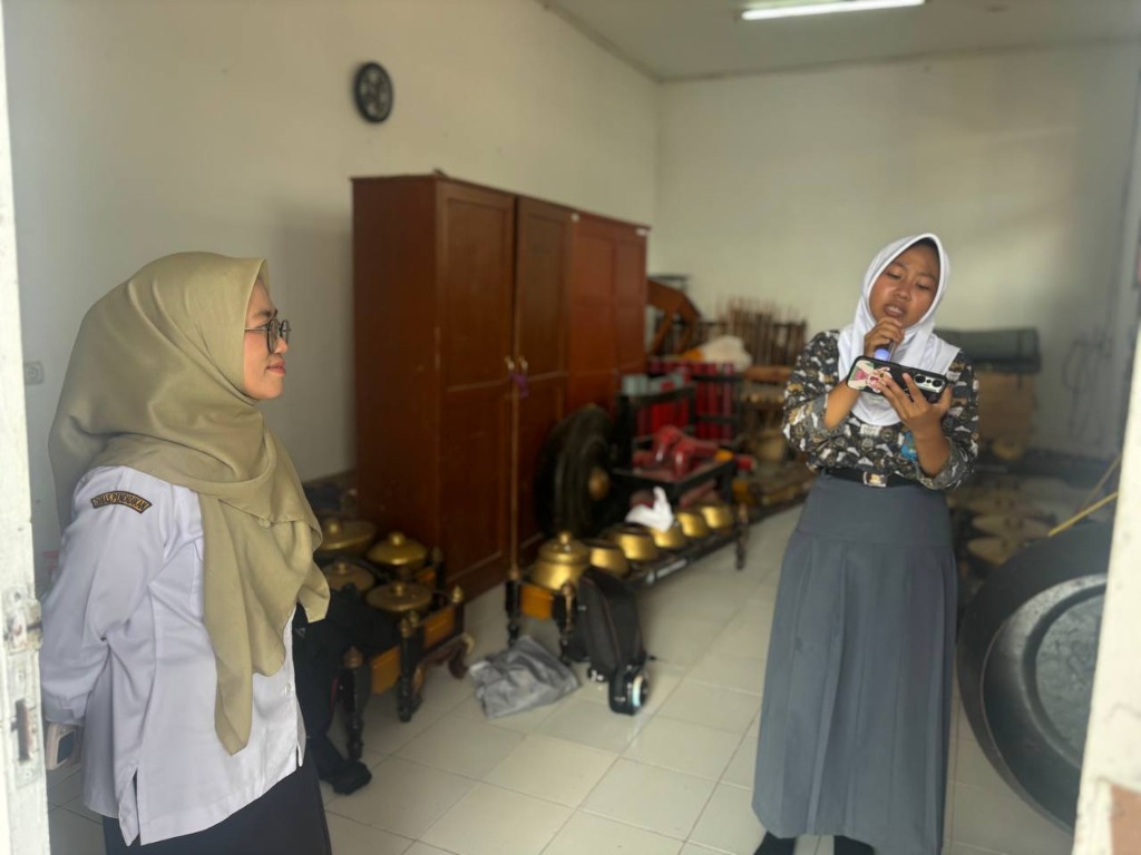 Pembina Bu Tia Nurhasanah, S.Pd. tersenyum menyimak latihan vokal siswa di ruang karawitan SMKN 1 Rongga yang dipenuhi instrumen gamelan