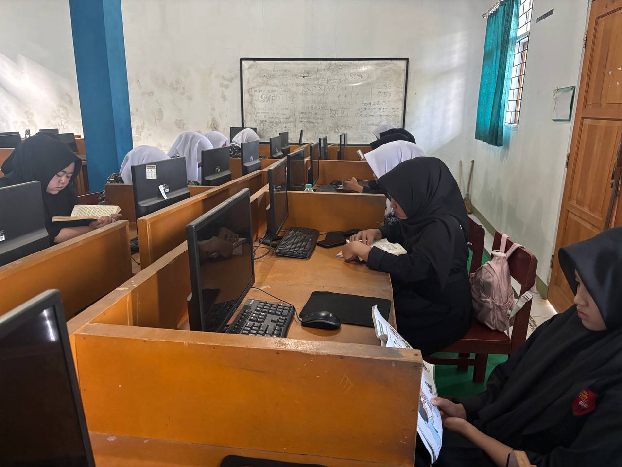 Deretan siswi SMKN 1 Rongga berseragam rapi membaca buku bersama-sama di meja laboratorium