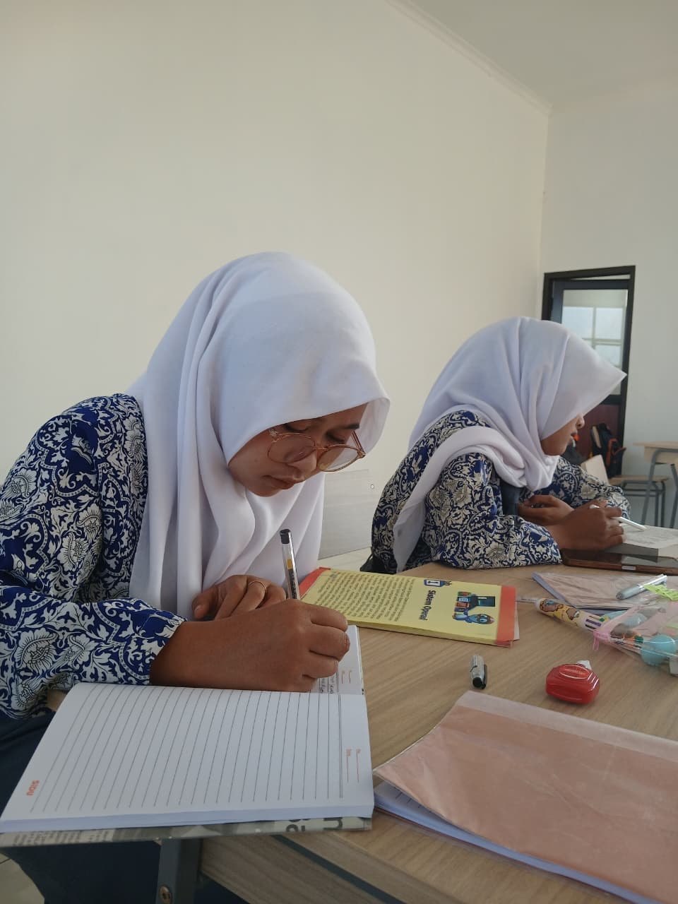 Siswi SMKN 1 Rongga berkacamata serius menulis rangkuman reflektif dari buku bacaan saat Literasi Rabu