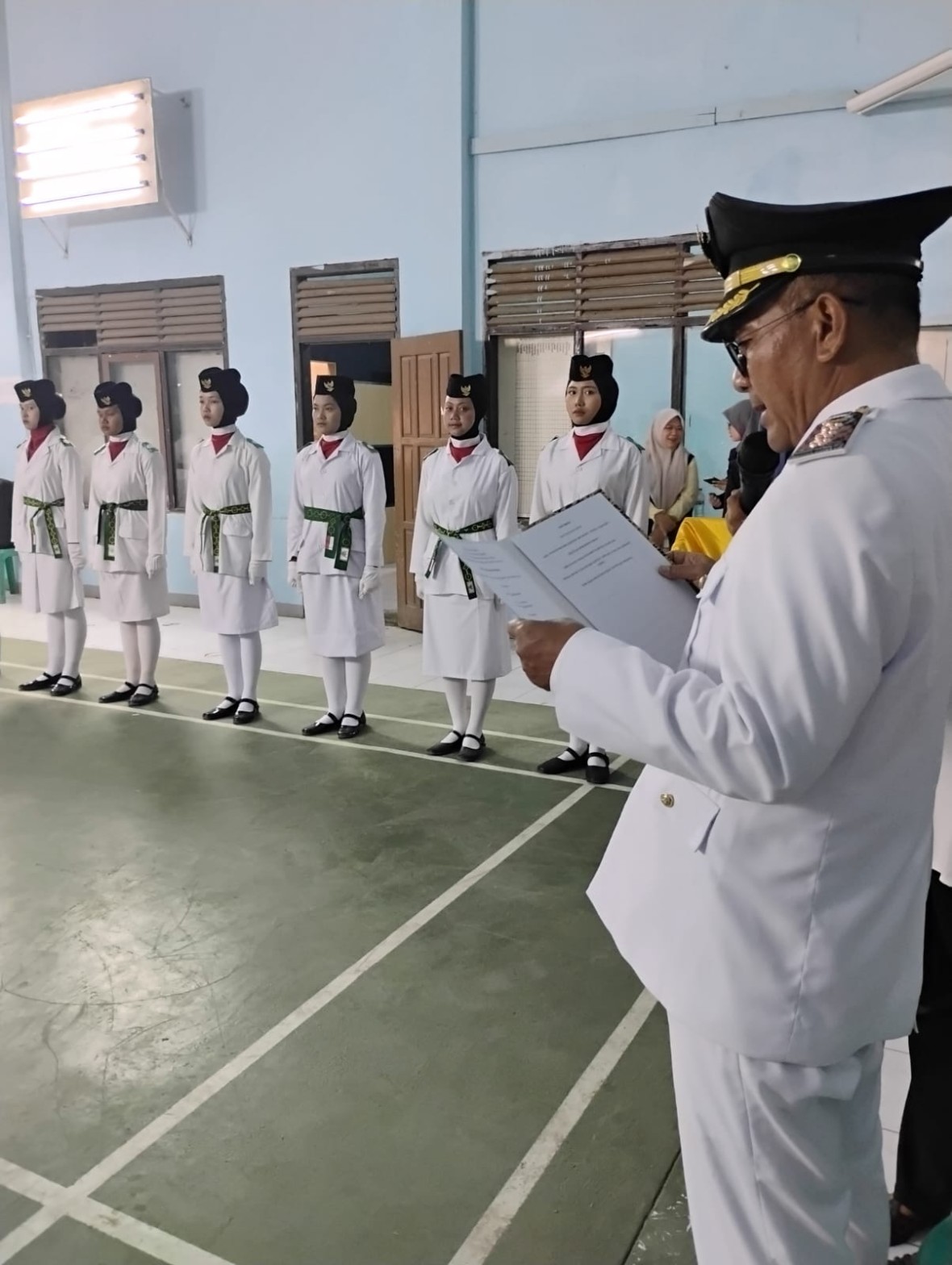 Pejabat memasang atribut pangkat pada anggota pasukan pengibar bendera berseragam putih dalam prosesi pengukuhan