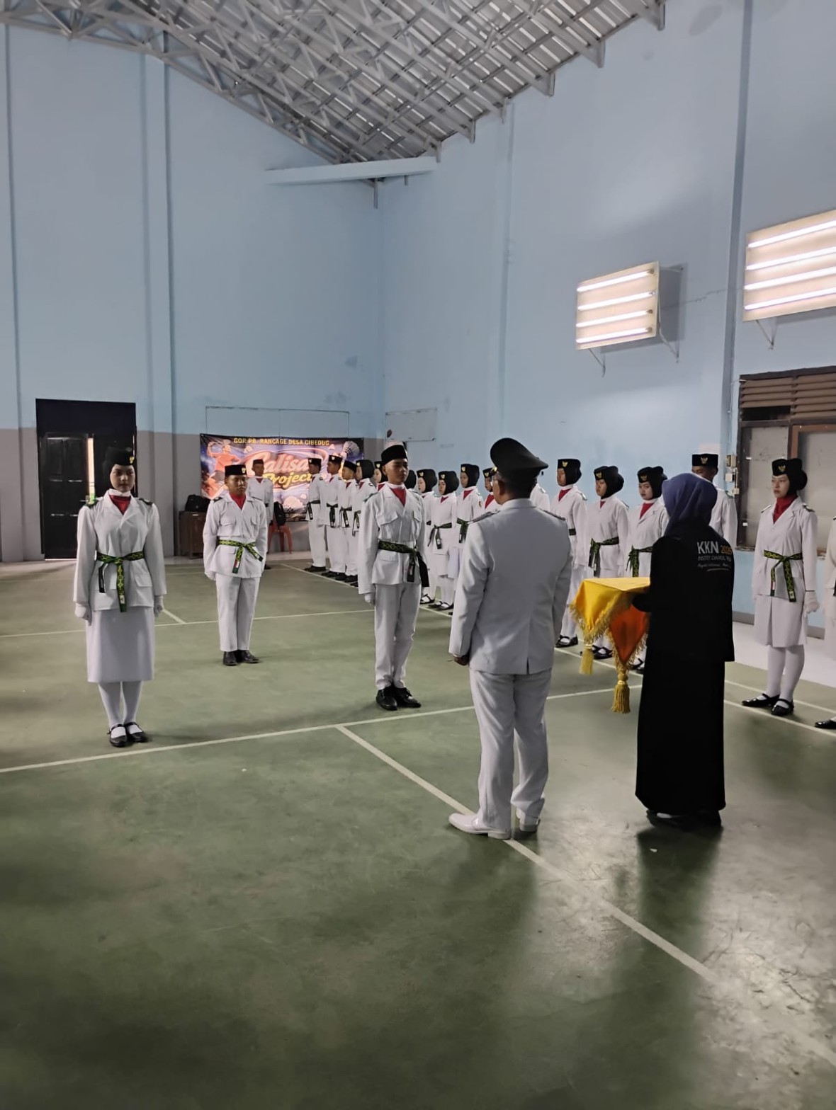 Enam petugas pengibar bendera berdiri berjajar menyimak pembacaan naskah pengukuhan oleh pejabat
