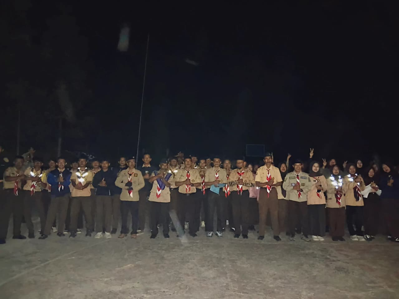 Ratusan anggota Pramuka berbaris rapat sambil menyalakan senter pada apel malam perkemahan HUT Pramuka se-Kwaran Kecamatan Rongga