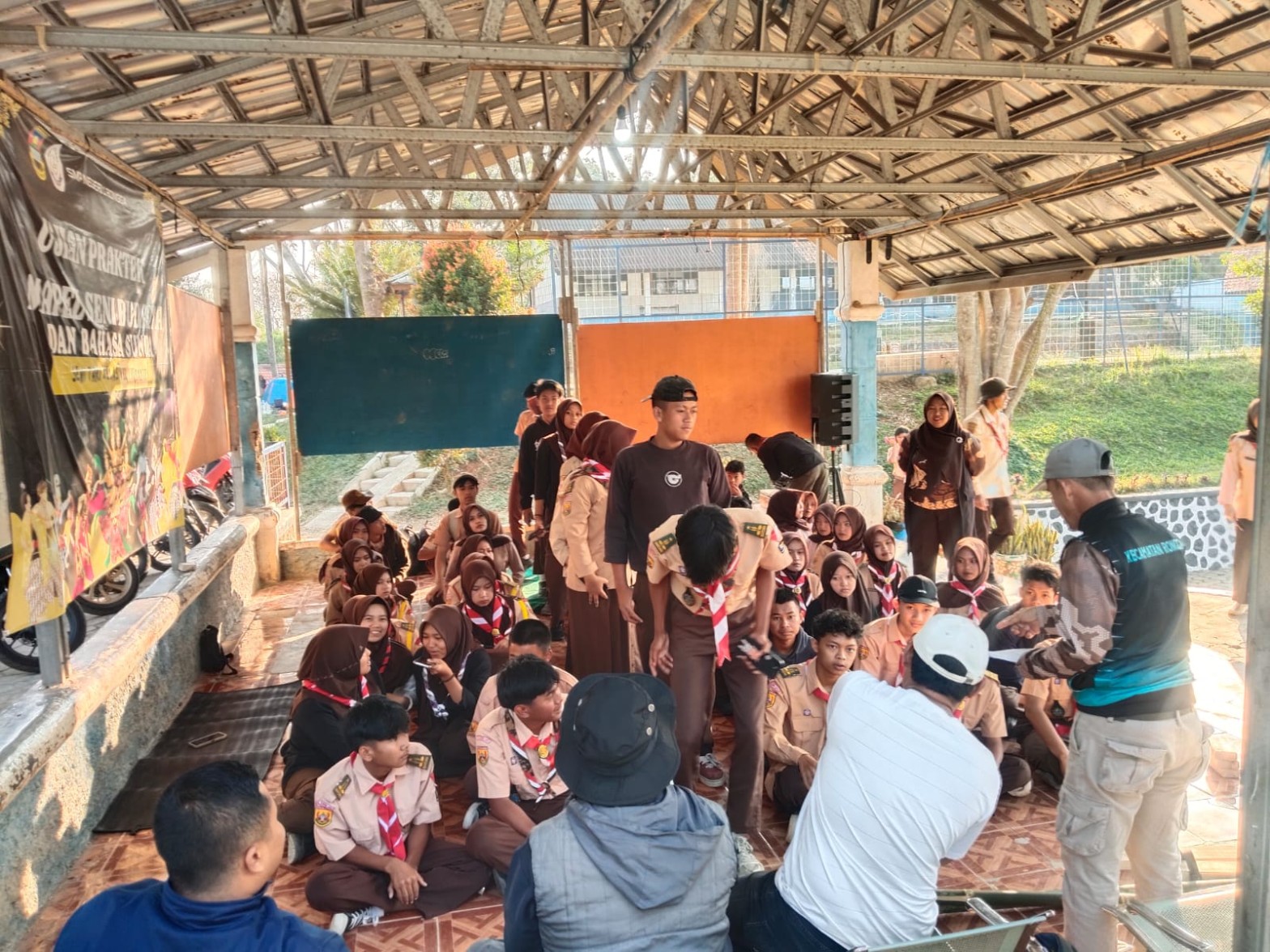 Peserta Pramuka duduk berkelompok di area terbuka mendengarkan pengarahan sebelum kegiatan longmarch dan hiking beregu perkemahan HUT Pramuka