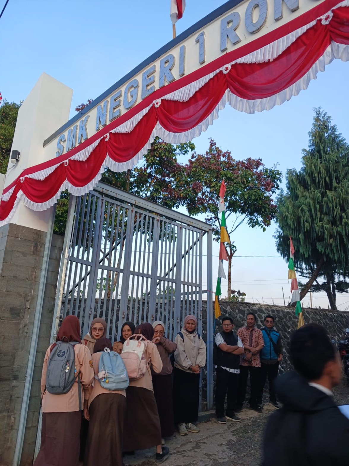 Siswa dan guru SMKN 1 Rongga tertawa bersama di gerbang sekolah pada pagi hari