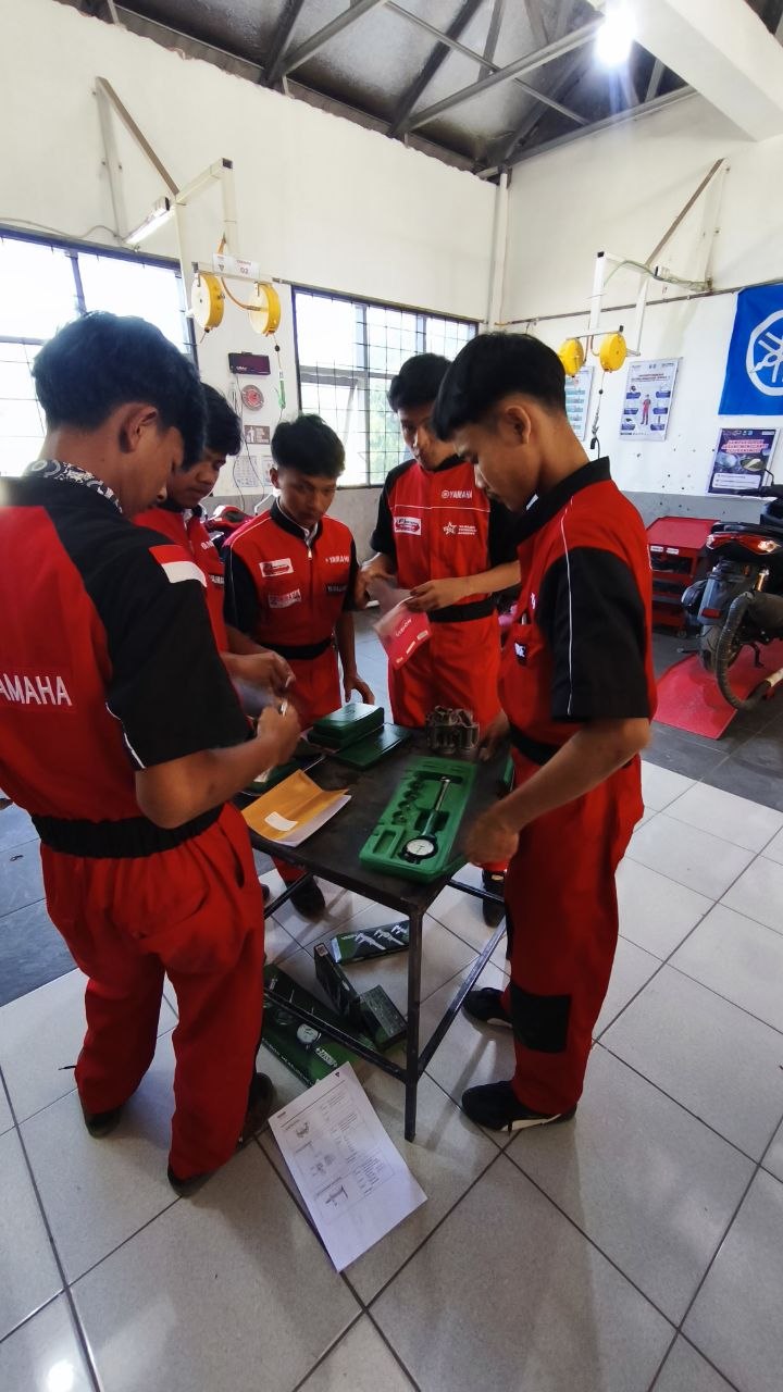 Siswa TSM SMKN 1 Rongga mencatat hasil pengukuran pada lembar kerja sambil memegang alat ukur di bengkel