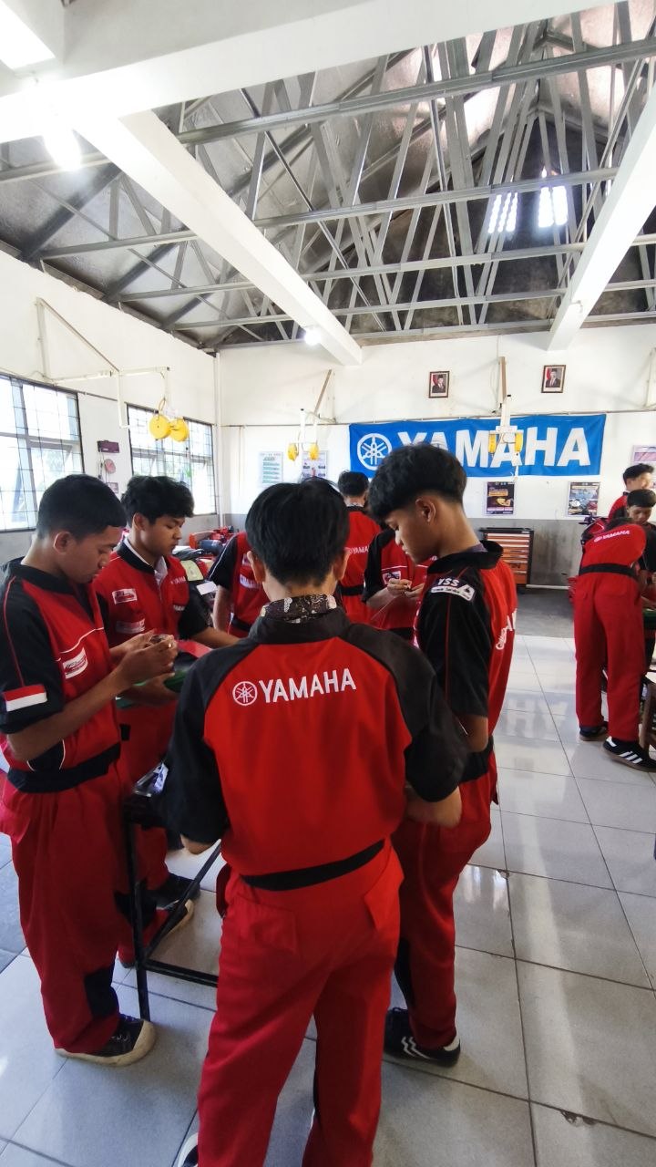 Sekelompok siswa TSM SMKN 1 Rongga berkumpul mengakhiri sesi praktik pengukuran di bengkel berlatar banner Yamaha