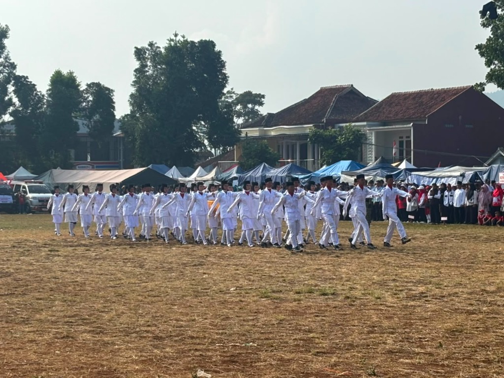 Pasukan Pengibar Bendera SMKN 1 Rongga melangkah tegap dan serempak melintasi lapangan upacara di hadapan tenda peserta dan masyarakat