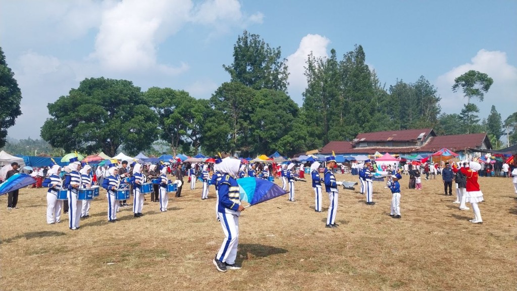 Penampilan Gita Bahana Marching Band SMKN 1 Rongga dengan kostum biru putih dan atraksi colour guard bendera di tengah Lapangan Rongga