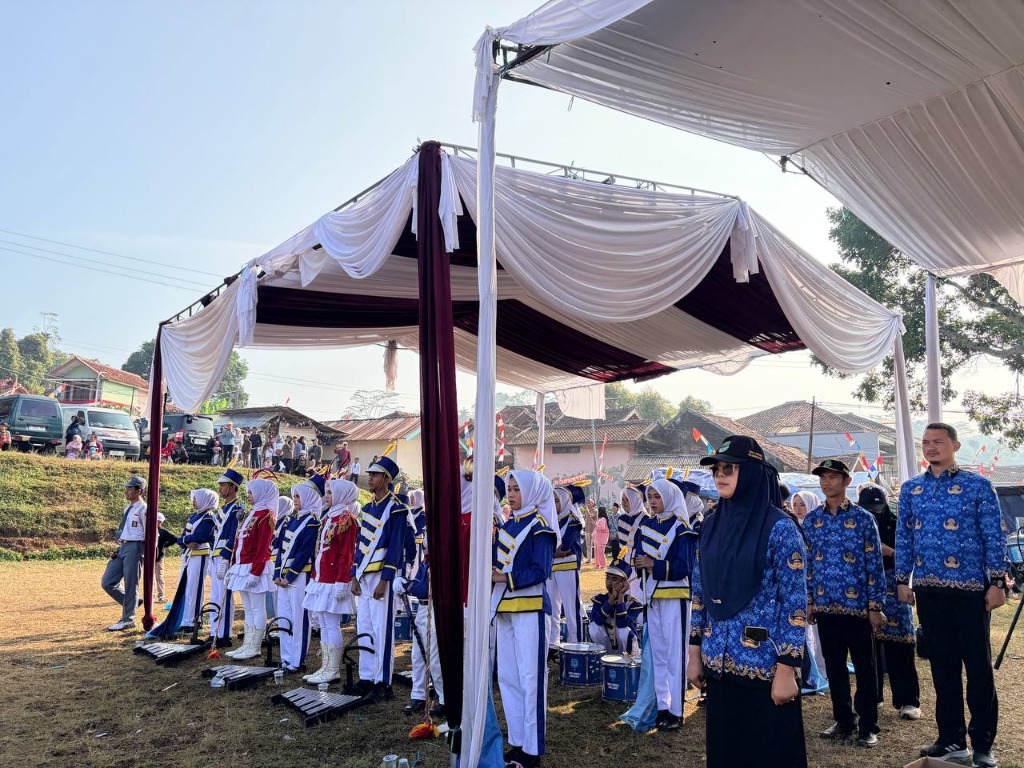 Personel marching band berseragam biru putih dan mayoret berseragam merah putih bersiap di bawah tenda didampingi pembina berseragam KORPRI