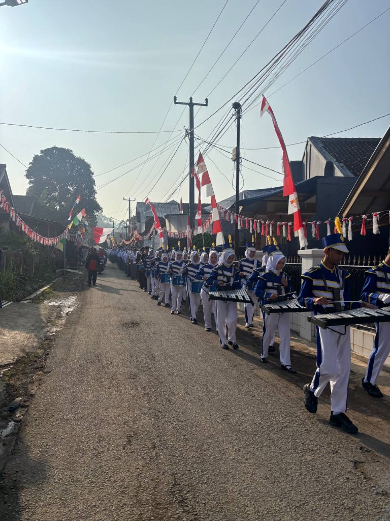 Barisan defile Gita Bahana Marching Band SMKN 1 Rongga menyusuri jalan desa yang dihiasi ornamen merah putih dalam rangka kirab HUT RI ke-81