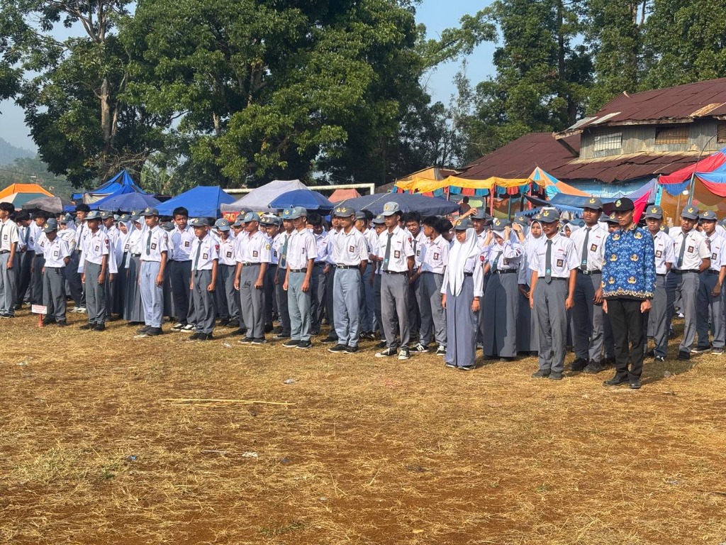 Pleton barisan siswa berseragam putih abu-abu lengkap dengan topi dan dasi berdiri tegap bersama pembina KORPRI di lapangan upacara